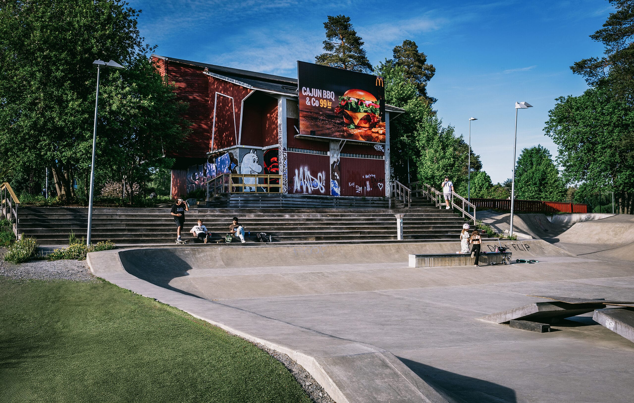 Utomhus skatepark med människor och reklamskylt